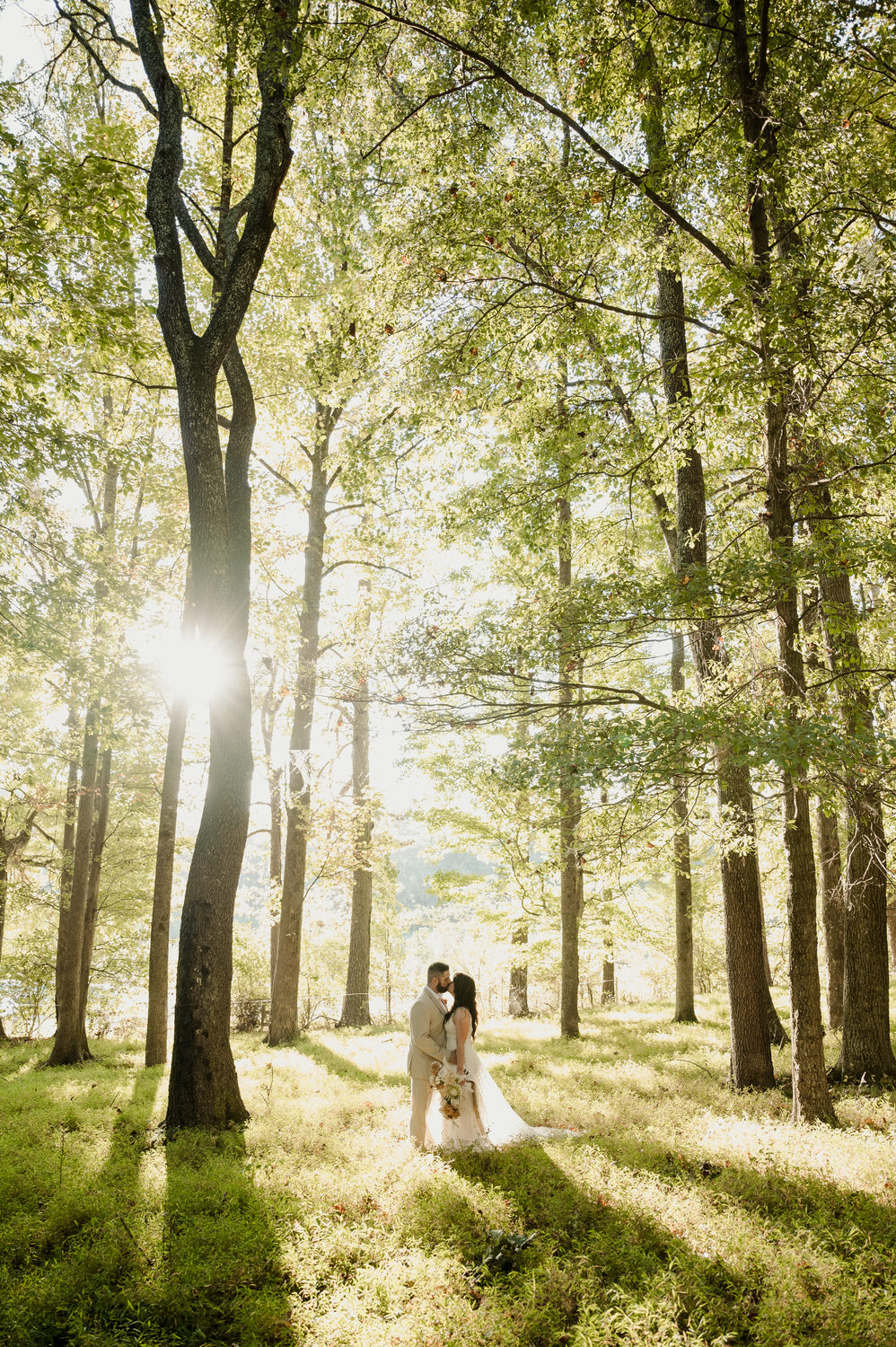 bride and groom in lush forest kissing 