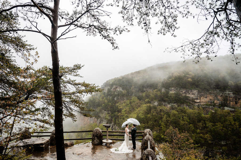 couple saying vows during their ceremony with umbrellas at Cloudland Canyon during their elopement